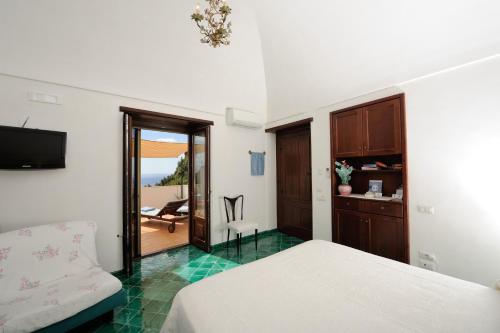 um quarto com uma cama, uma televisão e uma varanda em Tenuta Mamma Carmela em Amalfi