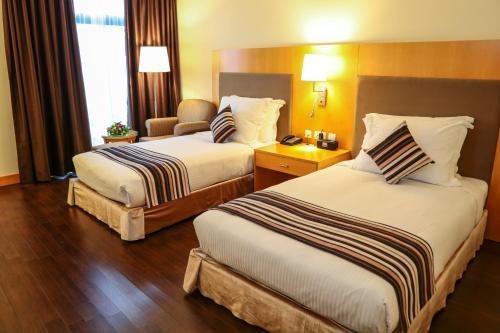 a hotel room with two beds and a chair at Ramada Addis, Addis Ababa in Addis Ababa