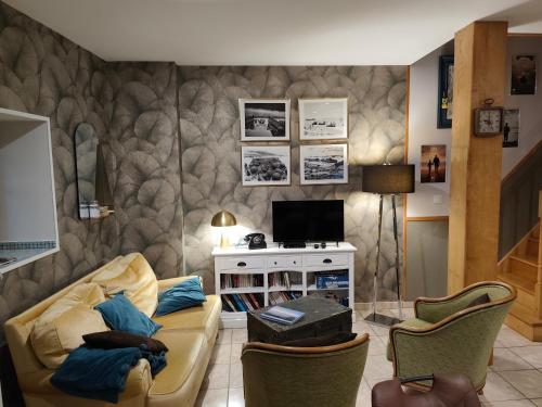een woonkamer met een bank en een tv bij La ferme aux chats in Formigny