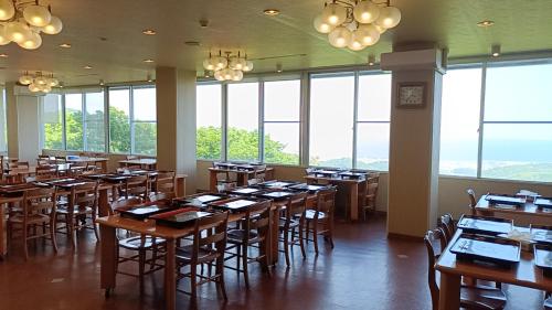ein Esszimmer mit Tischen, Stühlen und Fenstern in der Unterkunft 三河温泉酒店 in Nishio