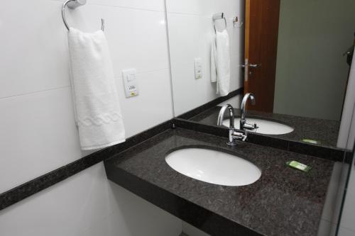 a bathroom with two sinks and a mirror at Hotel Recreio São Jorge in Jaboticabal