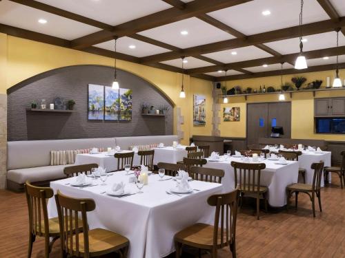 a dining room with white tables and chairs at Novotel Rayong Rim Pae Resort in Klaeng