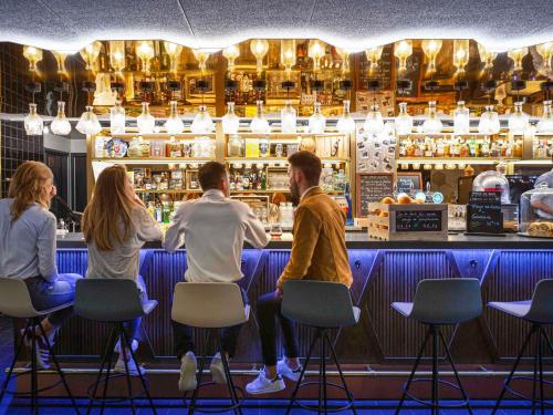 een groep mensen die aan een bar zitten bij Mercure Bordeaux Centre Ville in Bordeaux