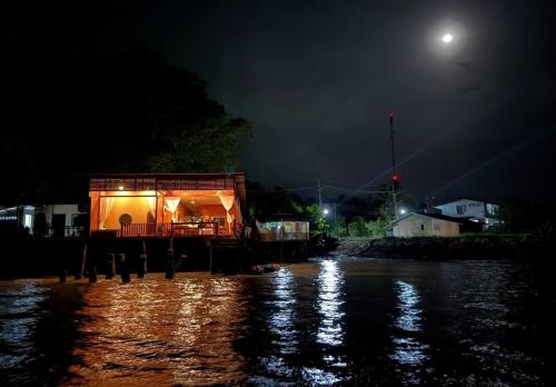 een huis op een dok in het water 's nachts bij 44Kohsaraihomestay 44เกาะสาหร่ายโฮมสเตย์ in Satun
