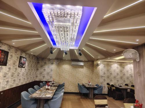 een eetkamer met tafels en stoelen en een kroonluchter bij HOTEL UMA PALACE in Gorakhpur