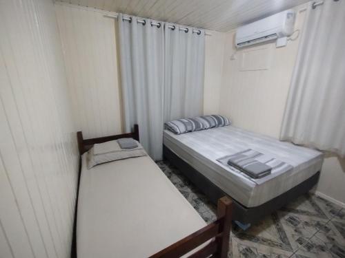 twee bedden in een kleine kamer met een raam bij Chalé com garagem fechada in Pântano Grande