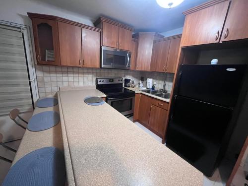 eine Küche mit einem schwarzen Kühlschrank und Holzschränken in der Unterkunft Casa Peace Haven Beach House Aguada in Aguada