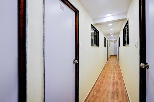 a hallway with white walls and a wooden floor at Hotel O Metro Galaxy inn in Mumbai
