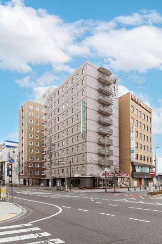 a large building on a city street with a road at Ace Inn Matsumoto in Matsumoto