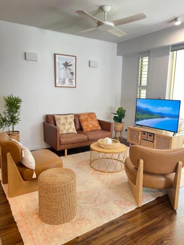 a living room with couches and a flat screen tv at Sunrise by Casuarina Beach in Casuarina