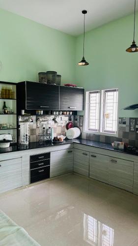 a kitchen with white cabinets and black counters at Parthipuram in Thottada
