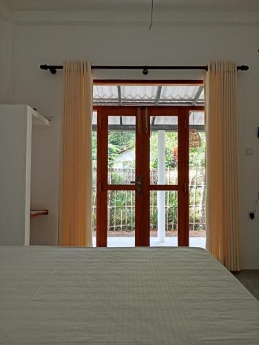 a bedroom with a bed and a large window at Emerald retreat in Ahangama