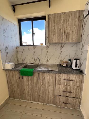 a kitchen with wooden cabinets and a sink at Lora's Haven Homes - Kikuyu Studio in Rungiri