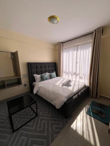 a bedroom with a bed and a window with a television at Lora's Haven Homes - Kikuyu Studio in Rungiri