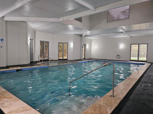 a large indoor swimming pool with blue water at The Basin Nest, a peaceful home at St Georges Basin in St Georges Basin