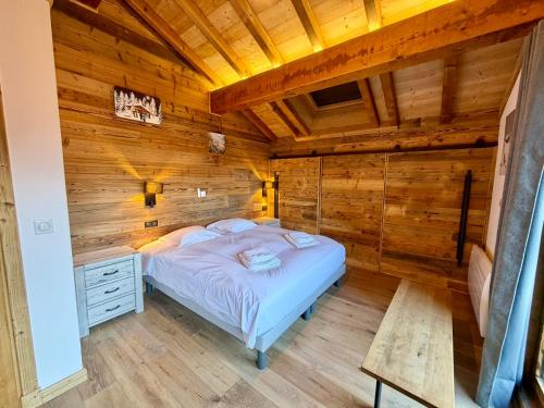 een slaapkamer met een bed in een kamer met houten wanden bij Le Refuge d'Ours, Champagny in Champagny-en-Vanoise