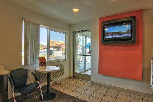 a waiting room with a tv and a table and chairs at Motel 6-Woodland, CA Sacramento Airport in Woodland