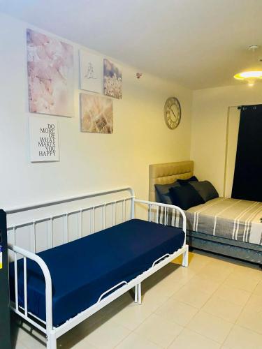 a bedroom with two beds and a clock on the wall at Plumera Condo Near Airport Malls & Schools with Elevator125 in Lapu Lapu City