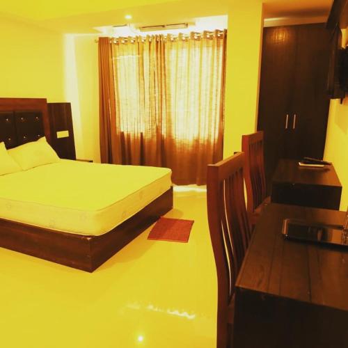 a bedroom with a bed and a table and a desk at Vinayaka Regency in Trivandrum