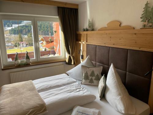 een slaapkamer met een groot bed met witte lakens en kussens bij Haus Romantika in Schattwald