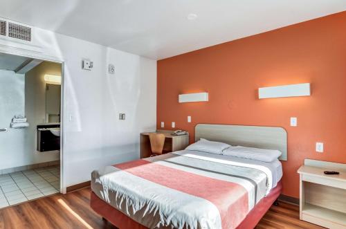 a bedroom with a bed with an orange wall at Motel 6 Fort Collins, CO in Fort Collins