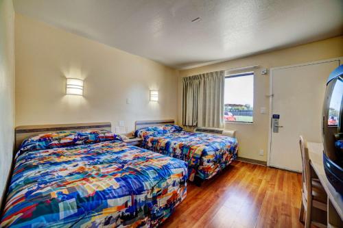 a hotel room with two beds and a window at Super 7 Inn in Bossier City