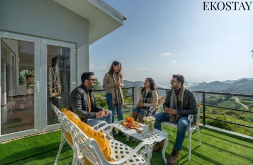 eine Gruppe von Menschen, die auf der Veranda eines Hauses sitzen in der Unterkunft EKOSTAY - Skyfall Cloud 9 Villa in Udagamandalam