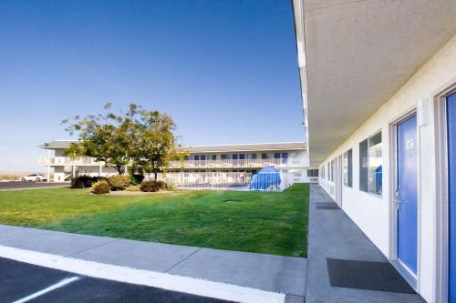 a building with a grass yard next to a building at Motel 6-Pendleton, OR in Pendleton