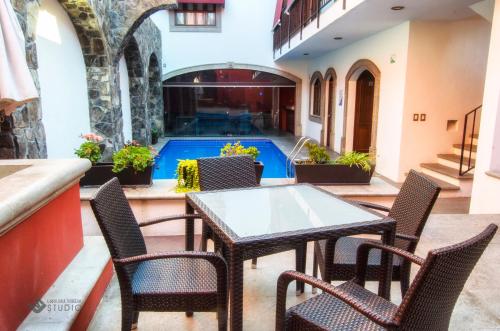 a patio with a table and chairs and a swimming pool at Hotel San Xavier in Querétaro