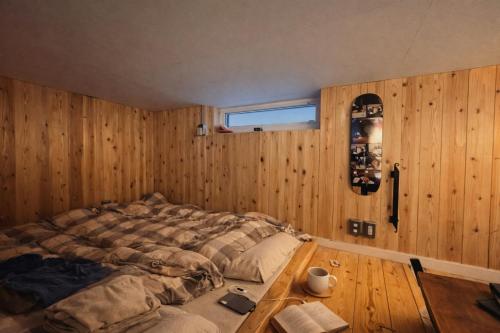 een slaapkamer met een bed en een houten wand bij Peanuts Nest in Nagano