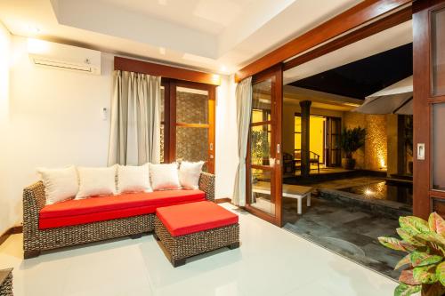 een woonkamer met een rotan bank en een rode bank bij Sanur Beach Villa - 3BR Private Pool in Sanur