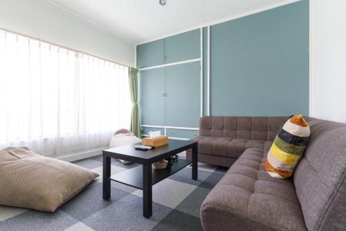 een woonkamer met een bank en een salontafel bij 富士吉田たまきや in Fujiyoshida