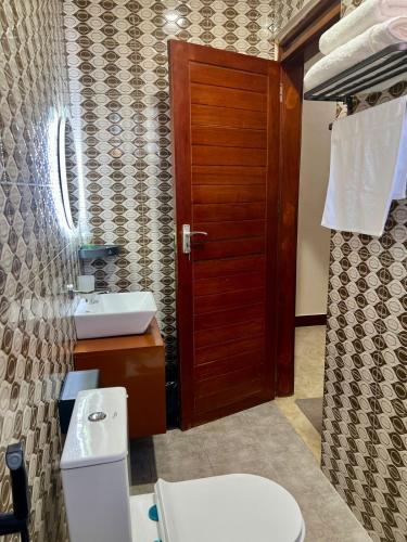 a bathroom with a toilet and a wooden door at Lucia Homes & Stays in Dodoma