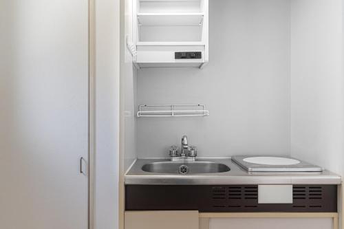 a small kitchen with a sink and a refrigerator at Peace 平和屋 in Osaka
