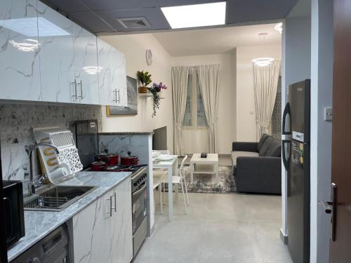 a kitchen with white cabinets and a living room at Studio in International City, Newly renovated with balcony! in Dubai