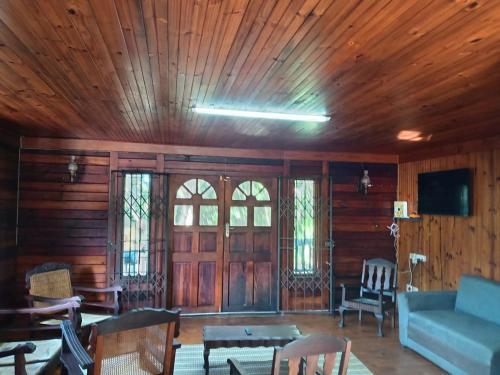 een woonkamer met een blauwe bank en houten wanden bij Jungle Cabin Leisure Bay in Port Edward