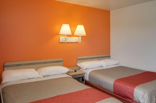 two beds in a room with orange walls at Motel 6 Gulfport, MS Airport in Gulfport