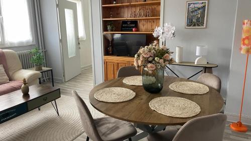 a dining room table with chairs and a vase of flowers at Appartement à 2 pas du centre, 2 chambres, parking in Aurillac