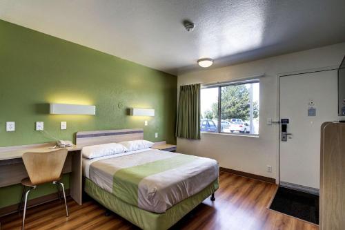 a bedroom with a bed and a desk and a window at Econo Lodge Midvale in Midvale