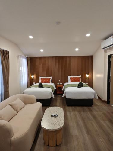 a hotel room with two beds and a couch at Tangerine Villa Patong in Patong Beach