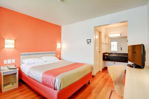 a bedroom with a bed with an orange wall at Motel 6-Southington, CT - Hartford in Southington