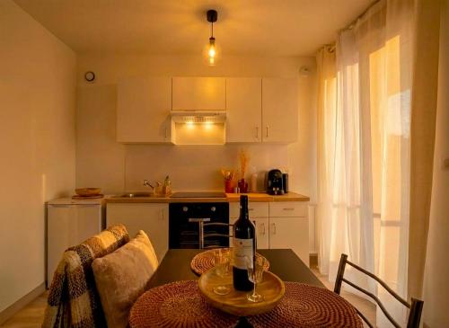 eine Küche mit einem Tisch mit einer Flasche Wein darauf in der Unterkunft La Porte de l'Échappée Verte - Salon Extérieur & Parking Privé in Albi