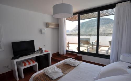 a bedroom with a bed and a tv and a window at Hotel Calachica Las Negras in Las Negras