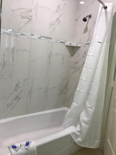 a white bathroom with a tub and a shower curtain at Americas Best Value Inn & Suites Spring / N. Houston in Spring