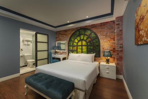 een slaapkamer met een bed en een bakstenen muur bij Hanoi La Selva Hotel in Hanoi