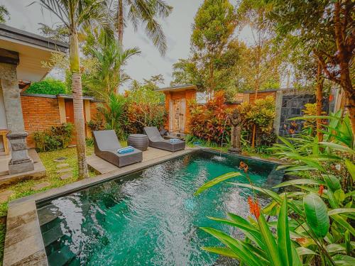 a swimming pool with two chairs and a house at Ubud Suarga Private Pool Villa in Ubud