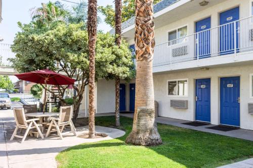 a table and chairs with an umbrella in front of a building at Motel 6-Bakersfield, CA - East in Bakersfield