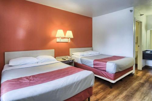 two beds in a hotel room with orange walls at Motel 6-New Cumberland, PA - Harrisburg - Hershey South in New Cumberland