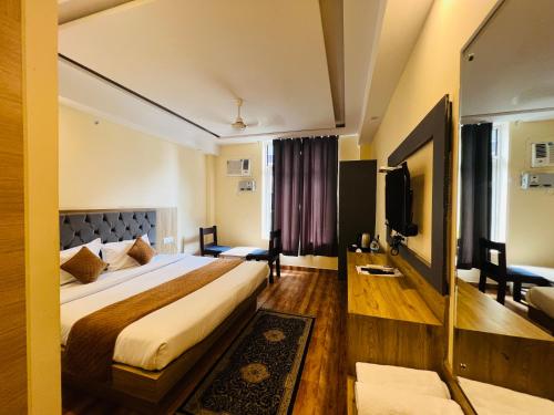 a hotel room with a bed and a tv at The Fragrance Hotel in Katra