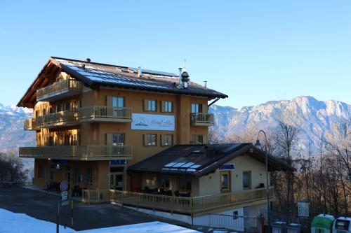 un grand bâtiment avec un balcon et des montagnes en arrière-plan dans l'établissement Hotel Alpe Bellaria, à Candriai